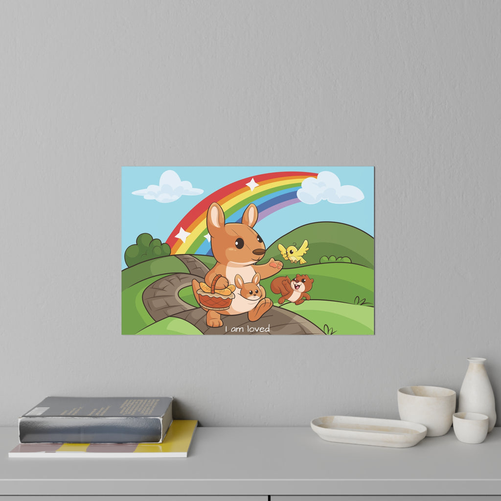 A 36 by 24 inch wall decal on a grey wall above a dresser and books. The wall decal has a scene of a kangaroo walking along a path through rolling hills, a rainbow in the background, and the phrase "I am loved" along the bottom.