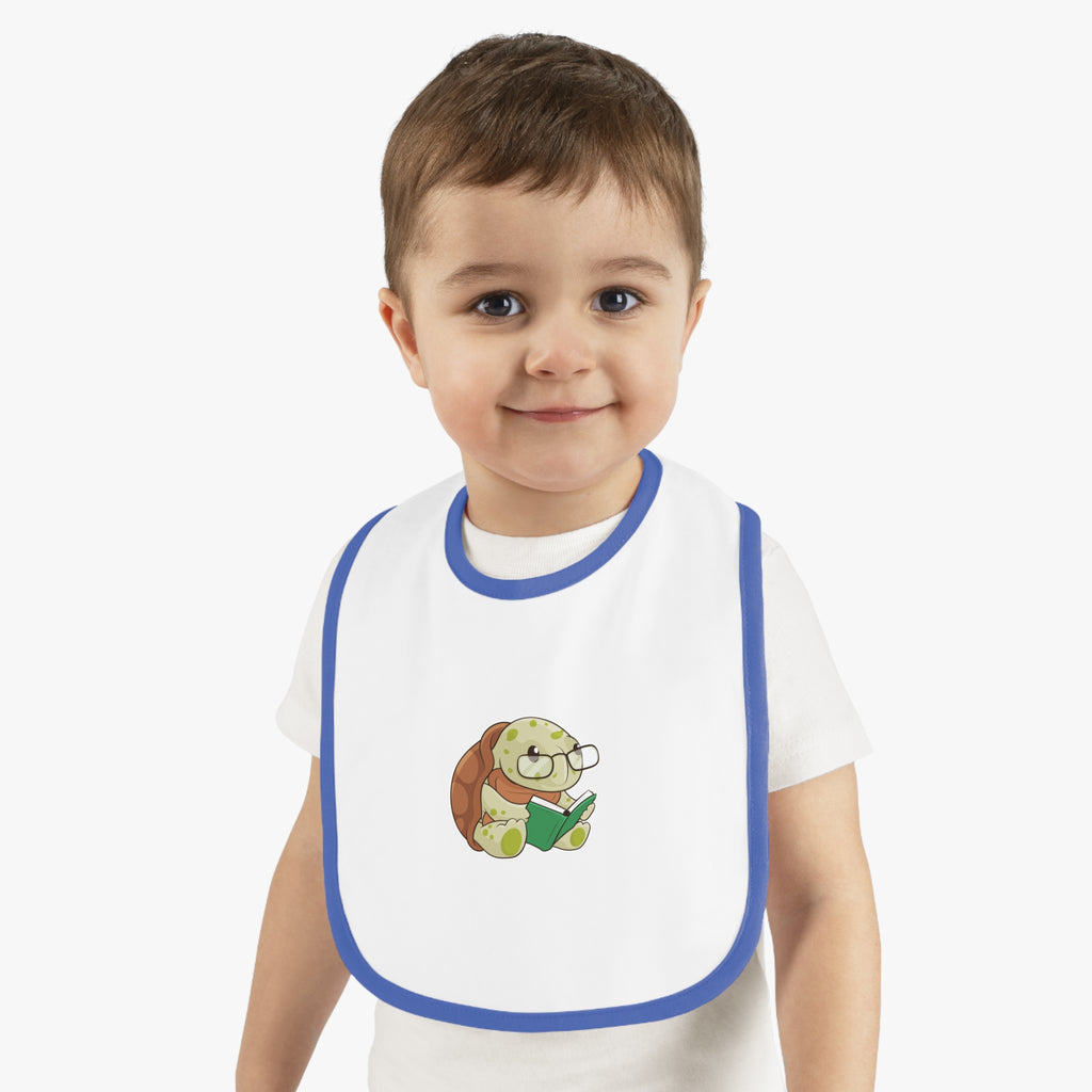 A little boy wearing a white baby bib with royal blue trim and a small picture of a turtle.