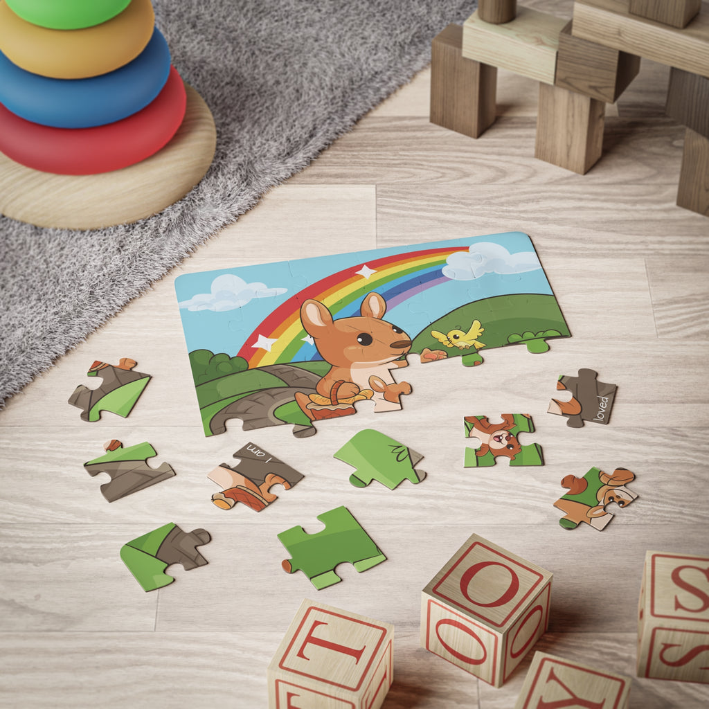 A 30 piece puzzle with a scene of a kangaroo walking on a path through rolling hills, a rainbow in the background, and the phrase "I am loved" along the bottom. The puzzle is partially assembled on the floor of a child's playroom.