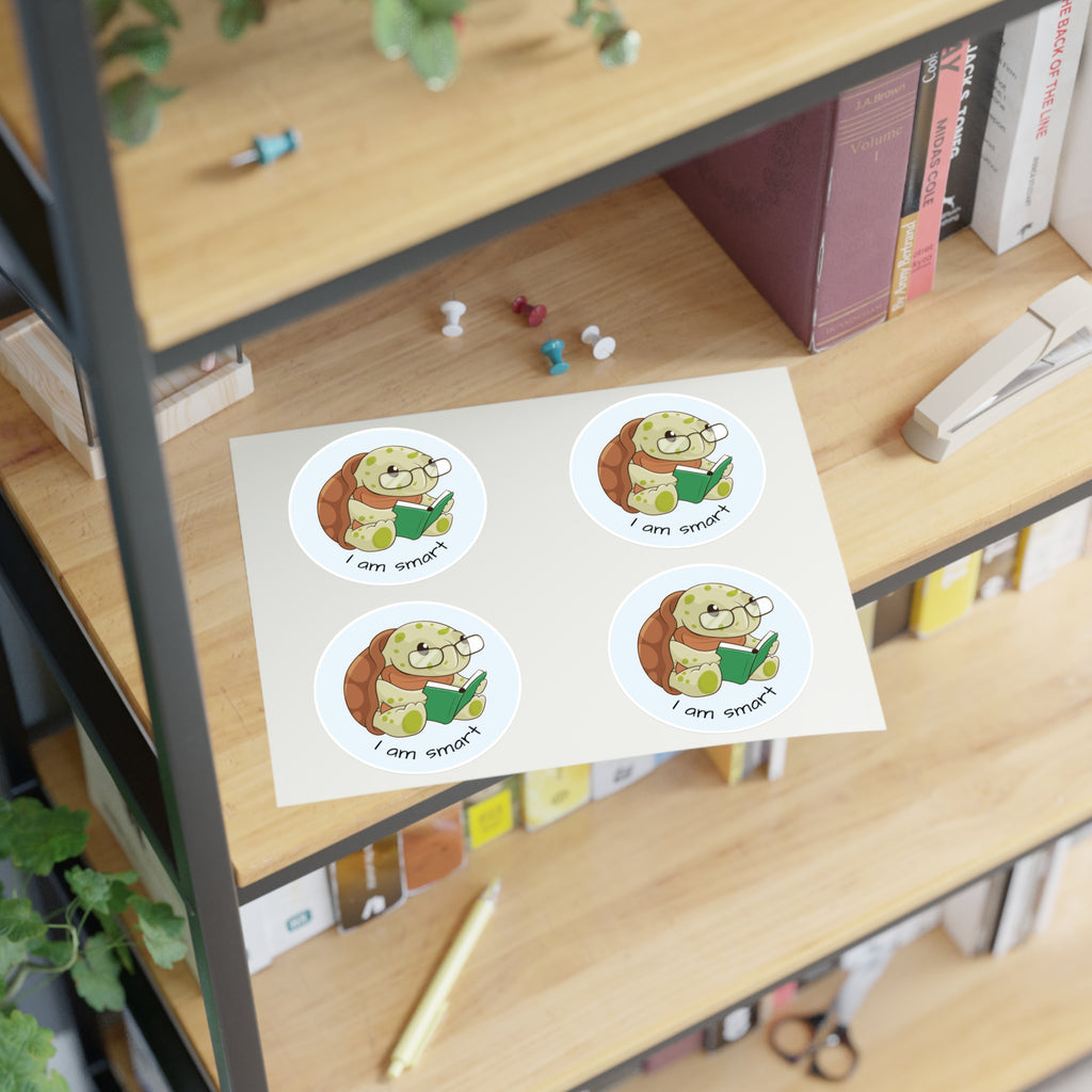 A sheet of 4 round stickers with a picture of a turtle that says I am smart. The sticker sheet sits on a shelf of a bookcase.