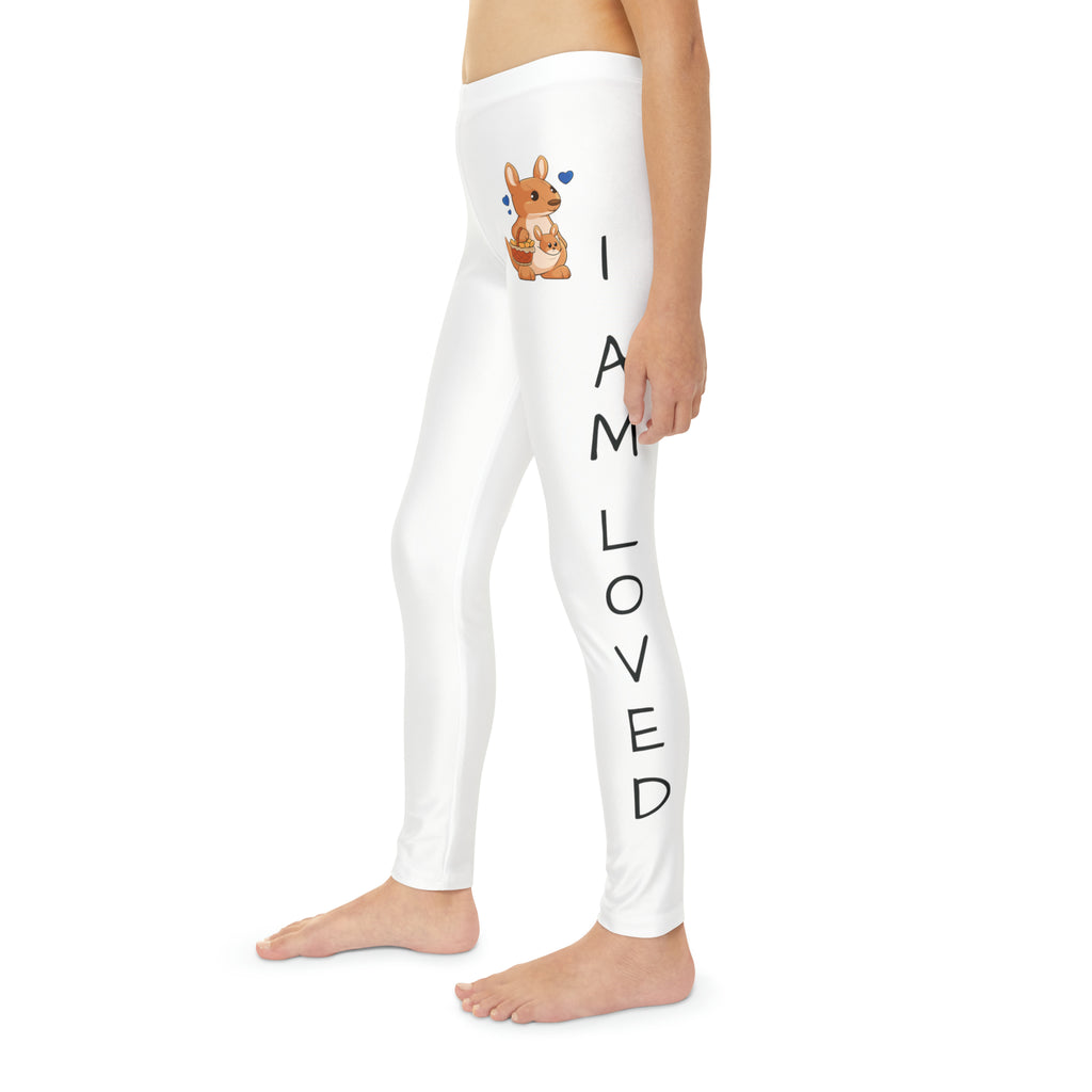 Left side-view of a child wearing white leggings with a picture of a kangaroo on the front left waist and the phrase "I am loved" read top to bottom on the side of each leg.