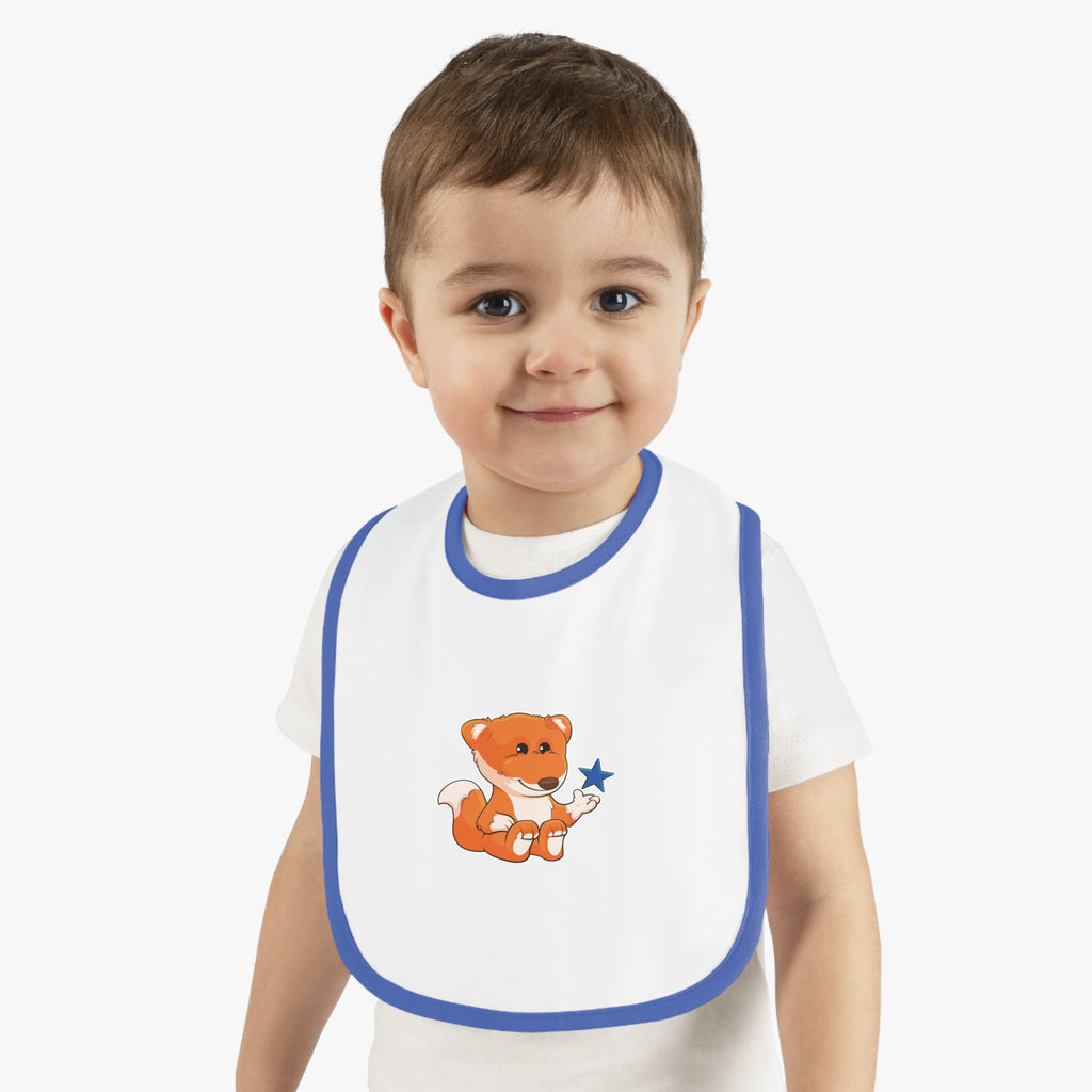 A little boy wearing a white baby bib with royal blue trim and a small picture of a fox.
