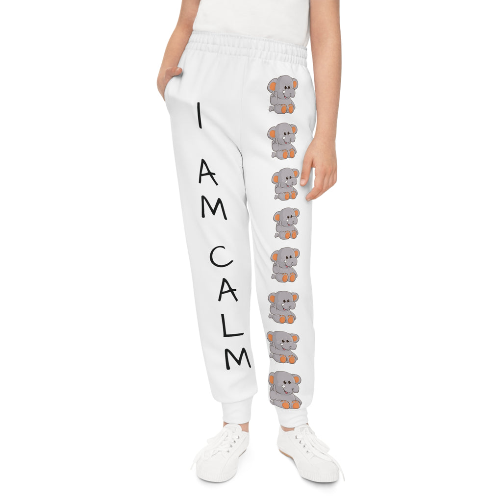 Front-view of a girl wearing white sweatpants with a line of elephants down the front left leg and the phrase "I am calm" down the front right leg.