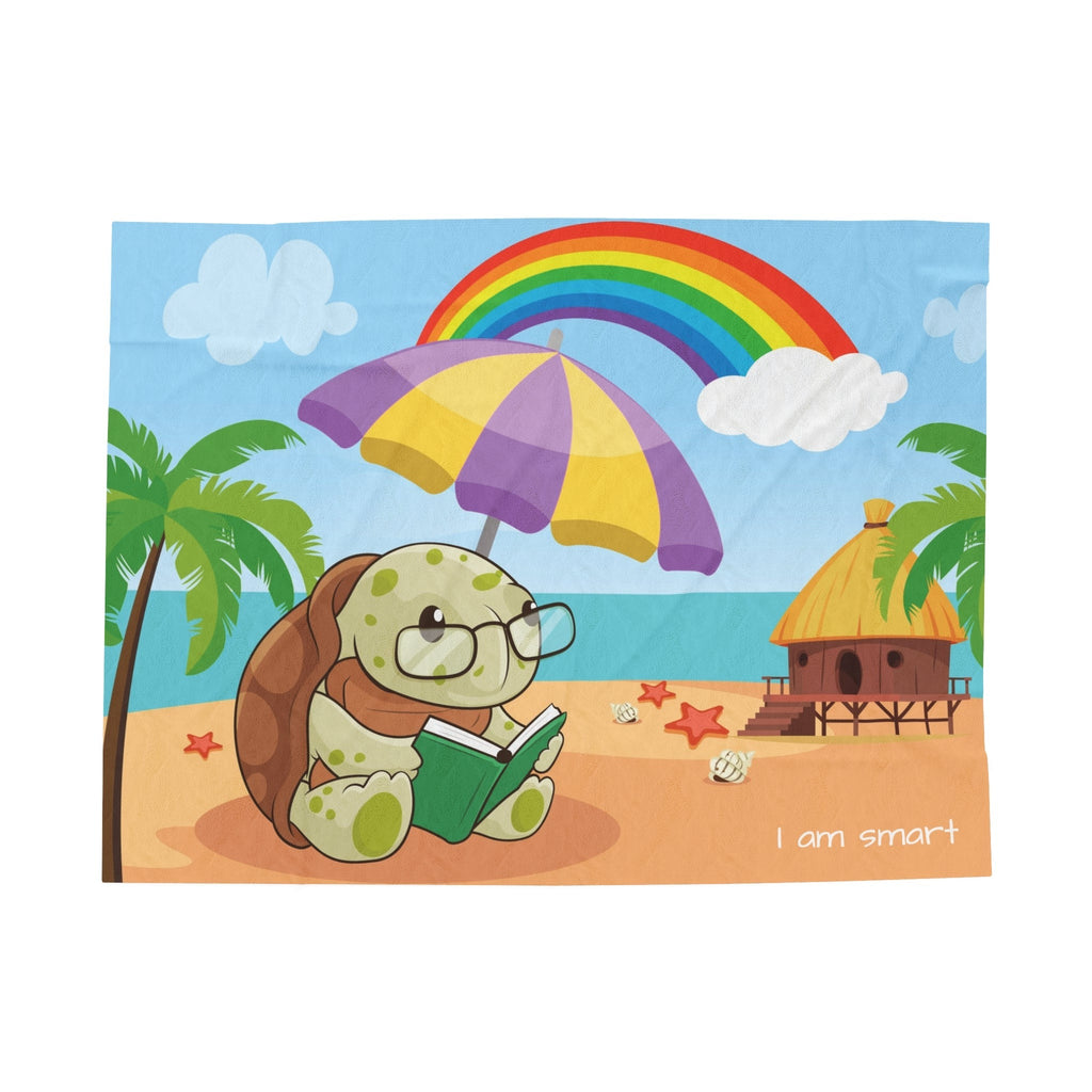 A blanket that has a scene of a turtle reading under an umbrella on the beach, a rainbow in the background, and the phrase "I am smart" along the bottom.
