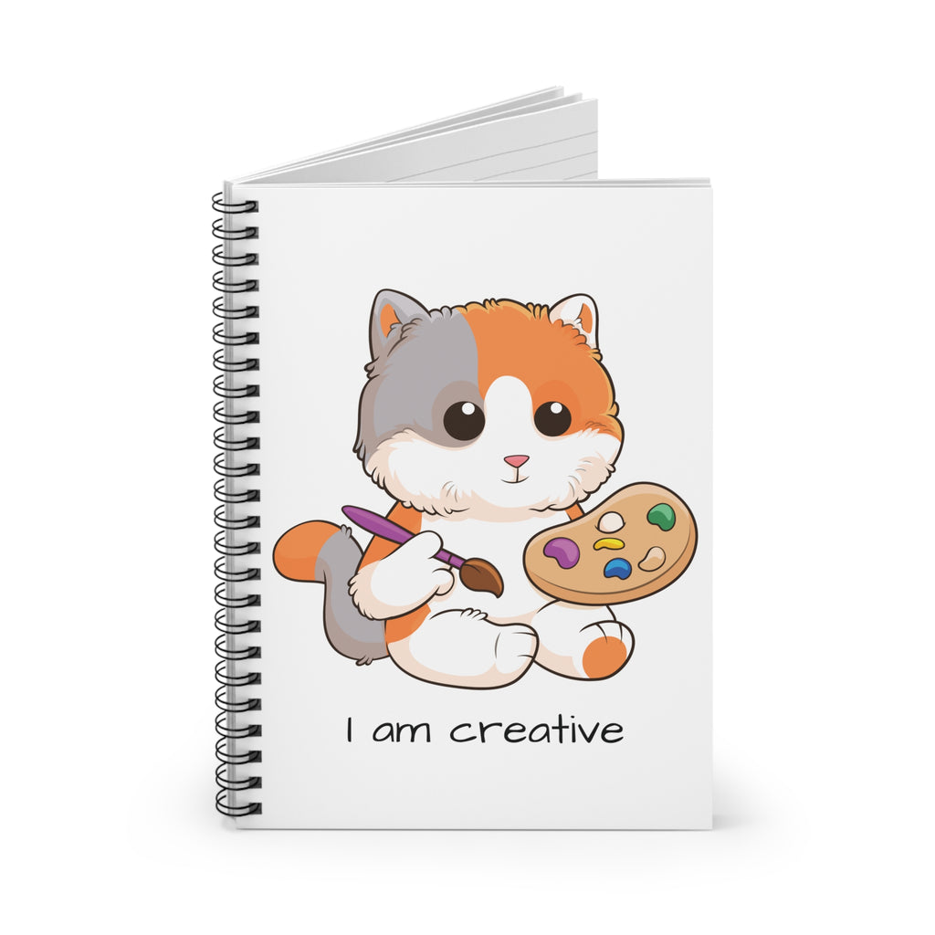 White spiral notebook standing up, featuring a picture of a cat that says I am creative on the front.