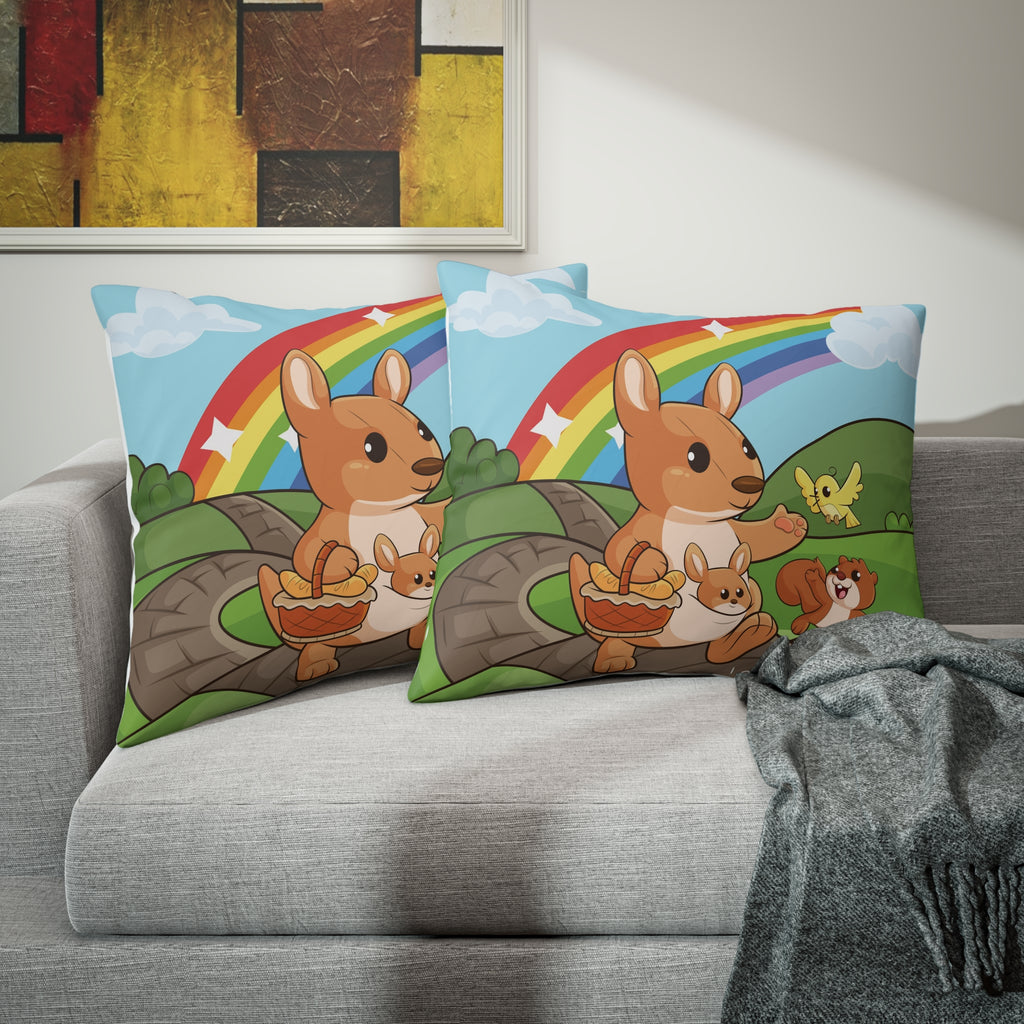 Two pillows sitting on a grey couch. The pillows have on pillowcases with a scene of a kangaroo walking along a path through rolling hills, a rainbow in the background, and the phrase "I am loved" along the bottom.