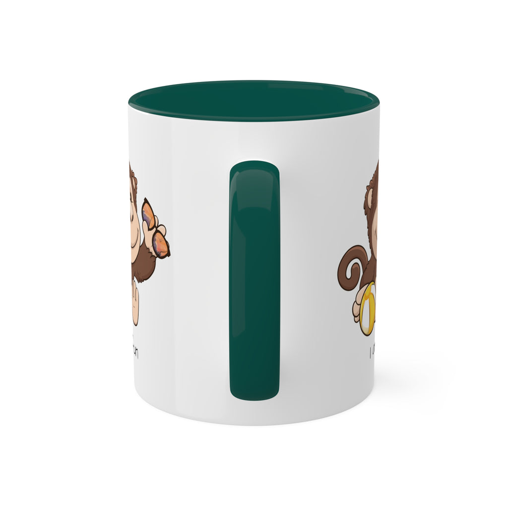 A white mug with a dark green handle and interior and a picture of a monkey that says I am fun.