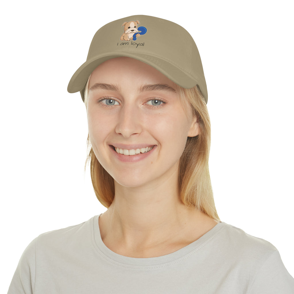 A female wearing a khaki baseball hat with a picture of a dog that says I am loyal.