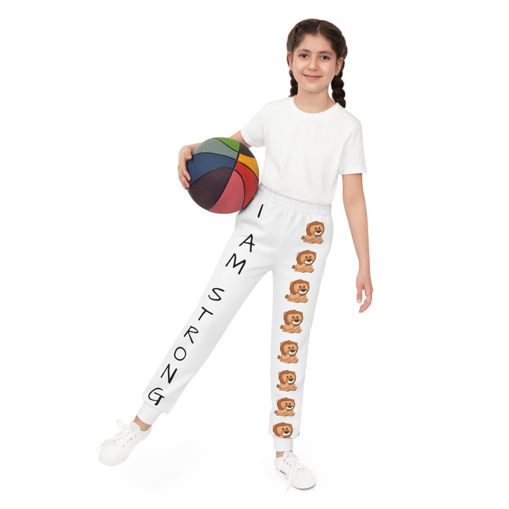 Front-view of a girl holding a basketball and wearing white sweatpants. The pants have a line of lions down the front left leg and the phrase "I am strong" down the front right leg.