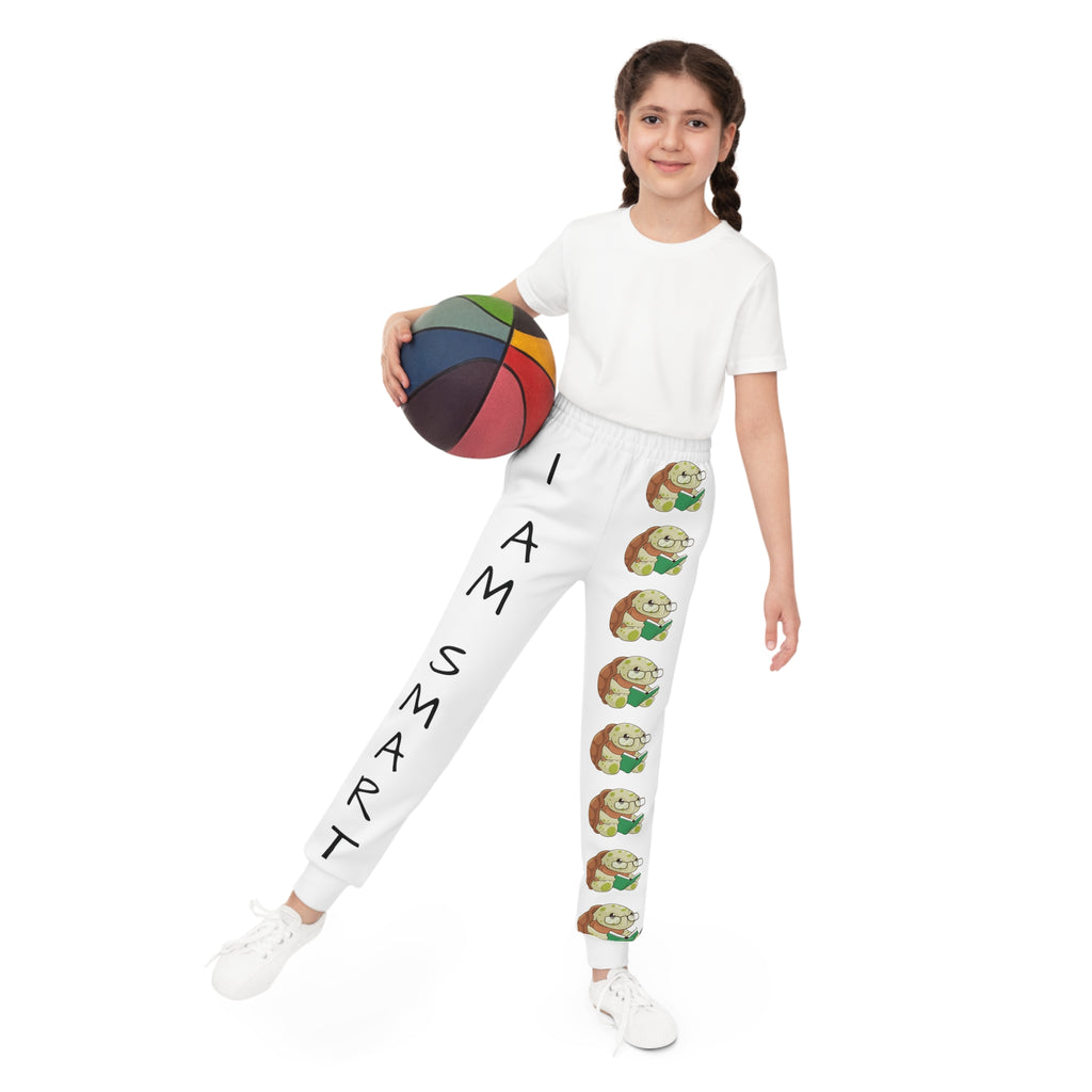 Front-view of a girl holding a basketball and wearing white sweatpants. The pants have a line of turtles down the front left leg and the phrase "I am smart" down the front right leg.