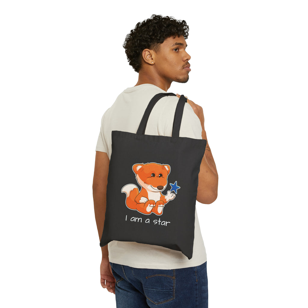 A man with a black tote bag over his shoulder, featuring a picture of a fox that says I am a star.