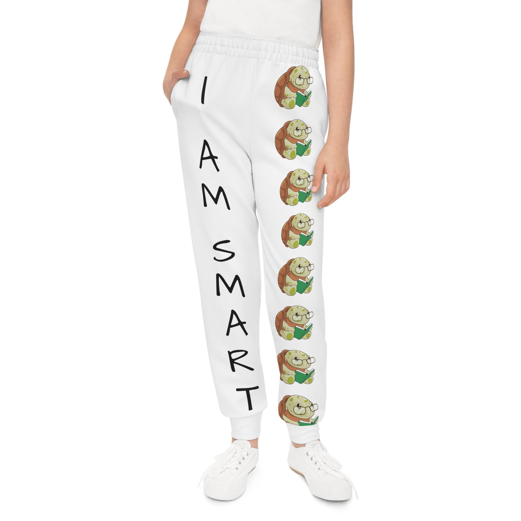 Front-view of a girl wearing white sweatpants with a line of turtles down the front left leg and the phrase "I am smart" down the front right leg.