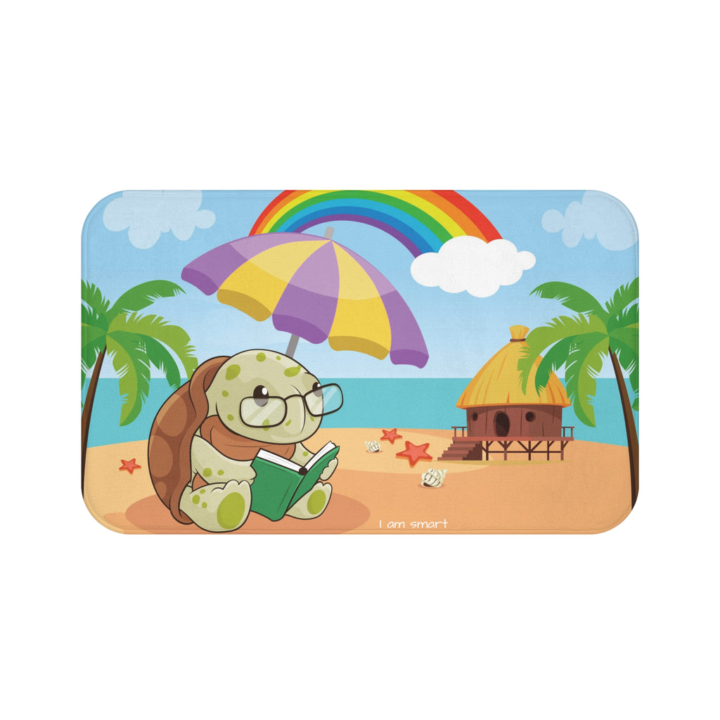 A 34 by 21 inch bath mat that has a scene of a turtle reading under an umbrella on a beach with a rainbow in the background and the phrase "I am smart" along the bottom.