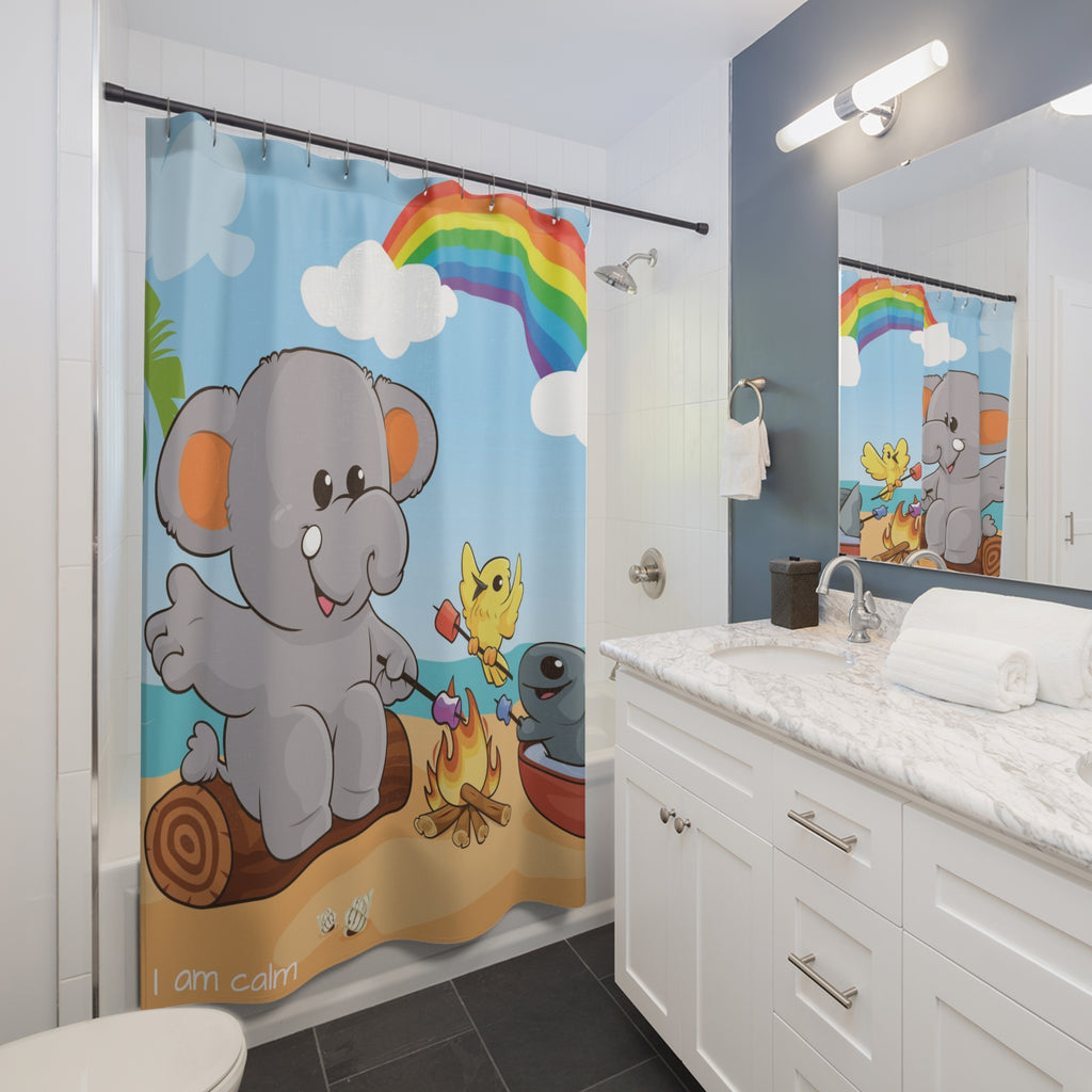 A shower curtain hanging from a rod in front of a built-in tub in a bathroom. The shower curtain has a scene of an elephant having a bonfire with a bird and fish on the beach, a rainbow in the background, and the phrase "I am calm" along the bottom.