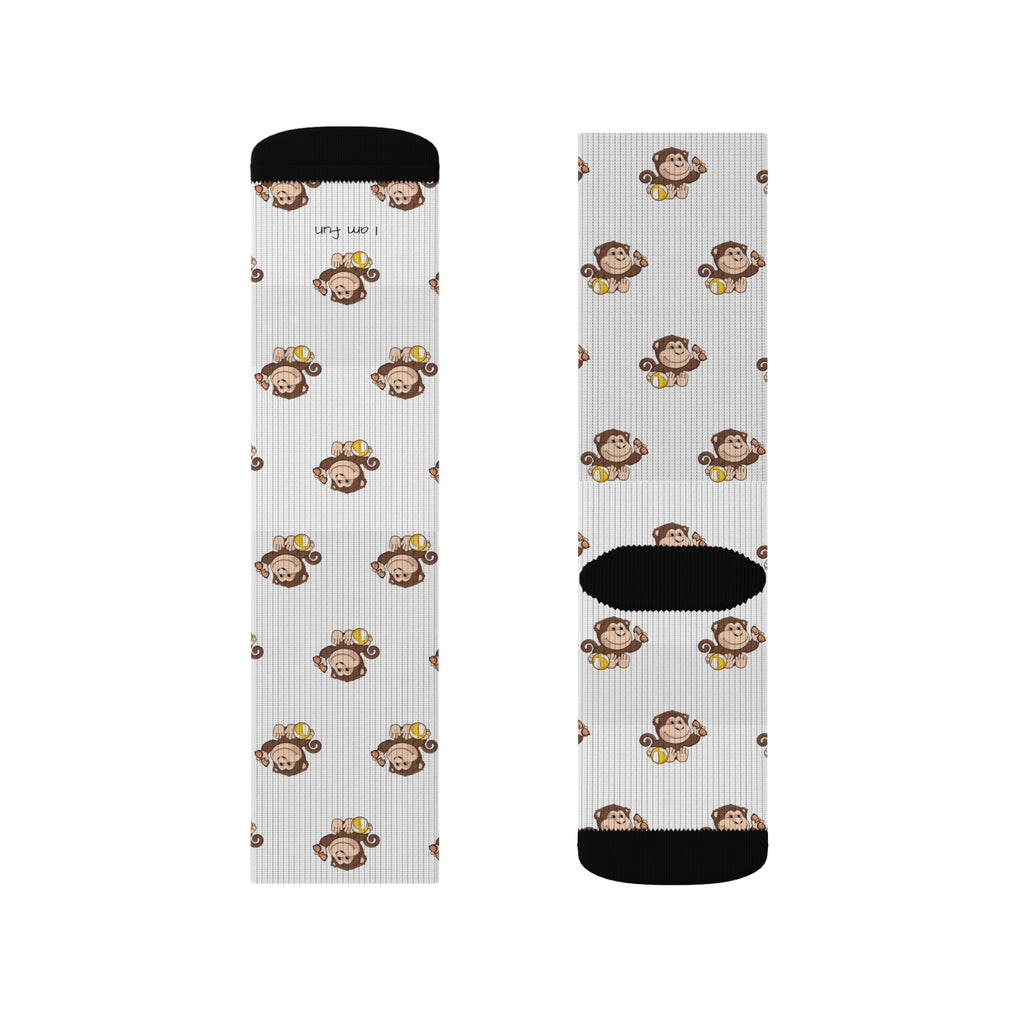 A pair of crew-length white socks with black toes and heels and a repeating pattern of a monkey.