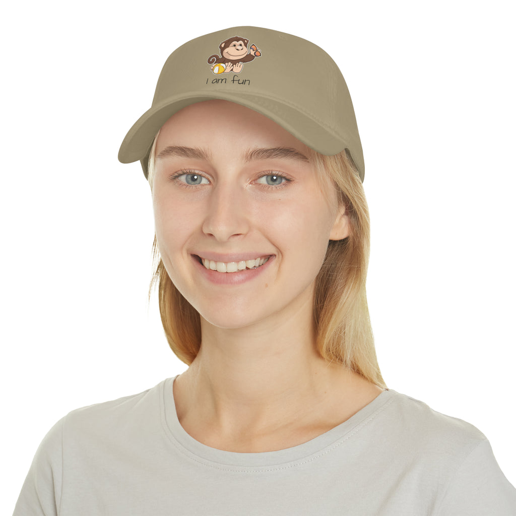 A female wearing a khaki baseball hat with a picture of a monkey that says I am fun.