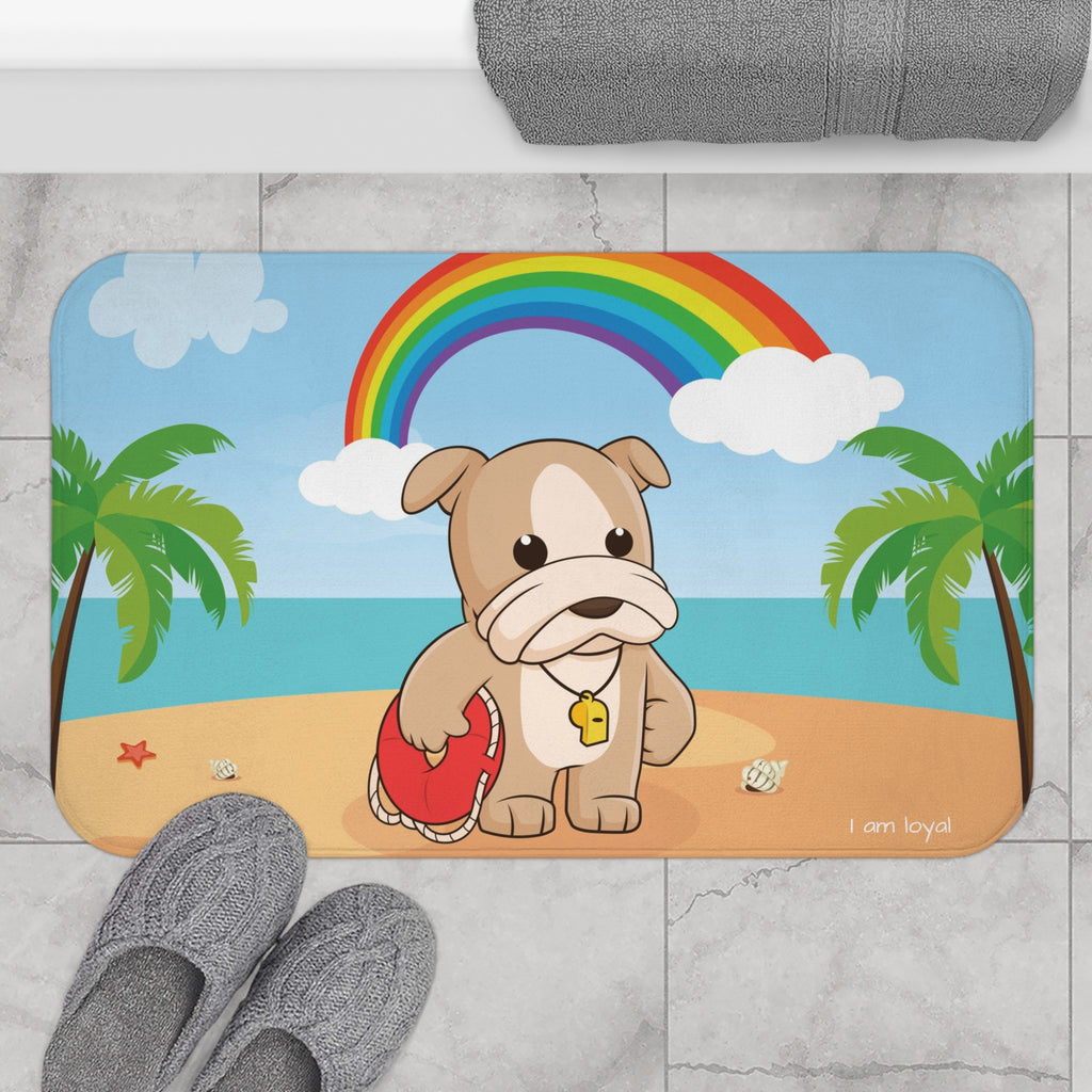 A 34 by 21 inch bath mat on the tiled floor of a bathroom. The bath mat has a scene of a dog lifeguard standing on a beach with a rainbow in the background and the phrase "I am loyal" along the bottom.