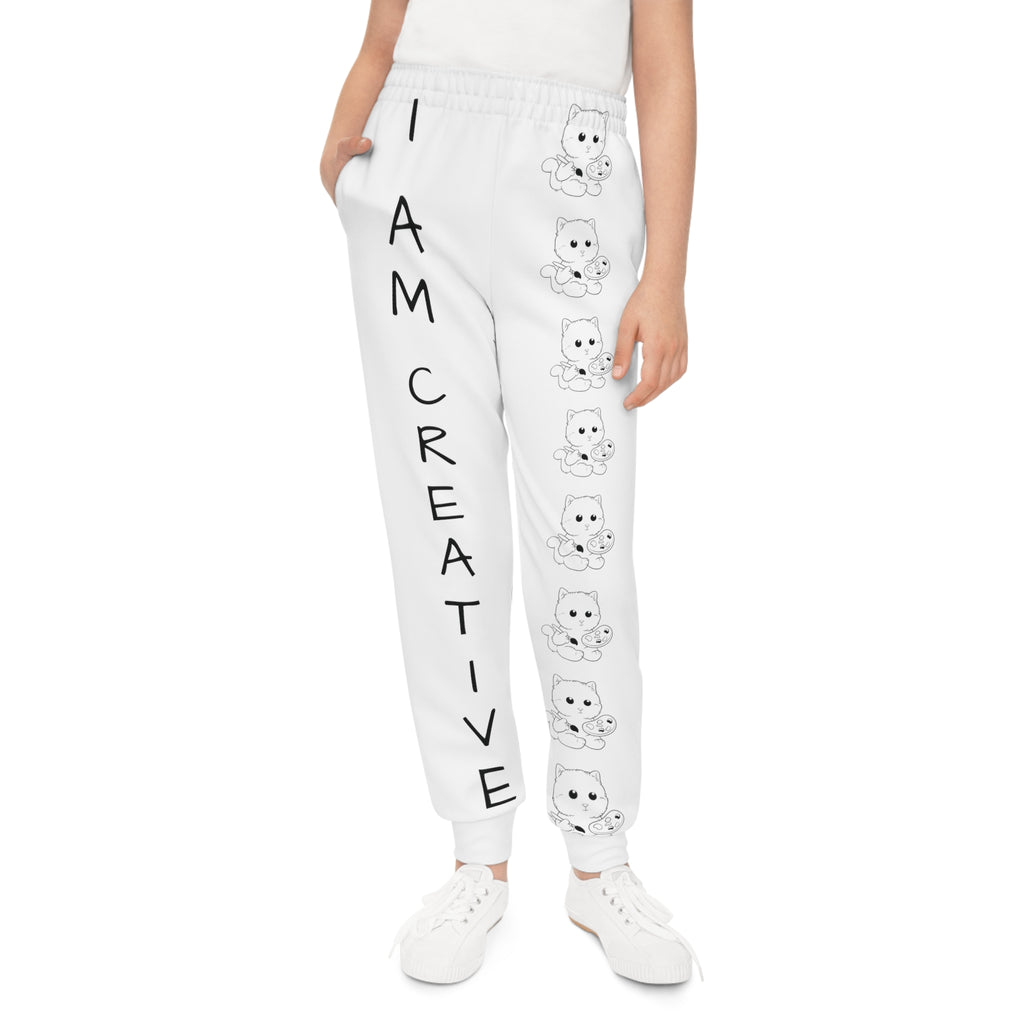 Front-view of a girl wearing white sweatpants with a line of black and white cats down the front left leg and the phrase "I am creative" down the front right leg.