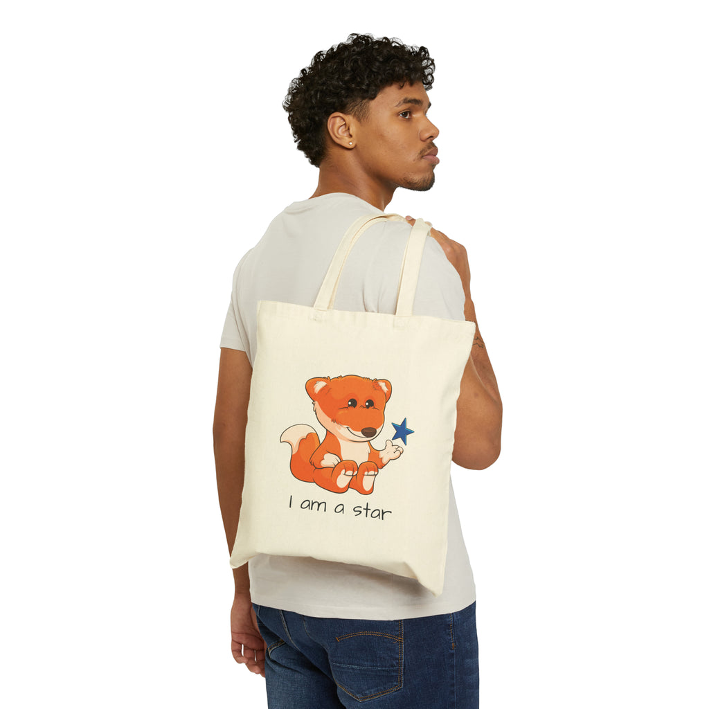 A man with a natural tan tote bag over his shoulder, featuring a picture of a fox that says I am a star.