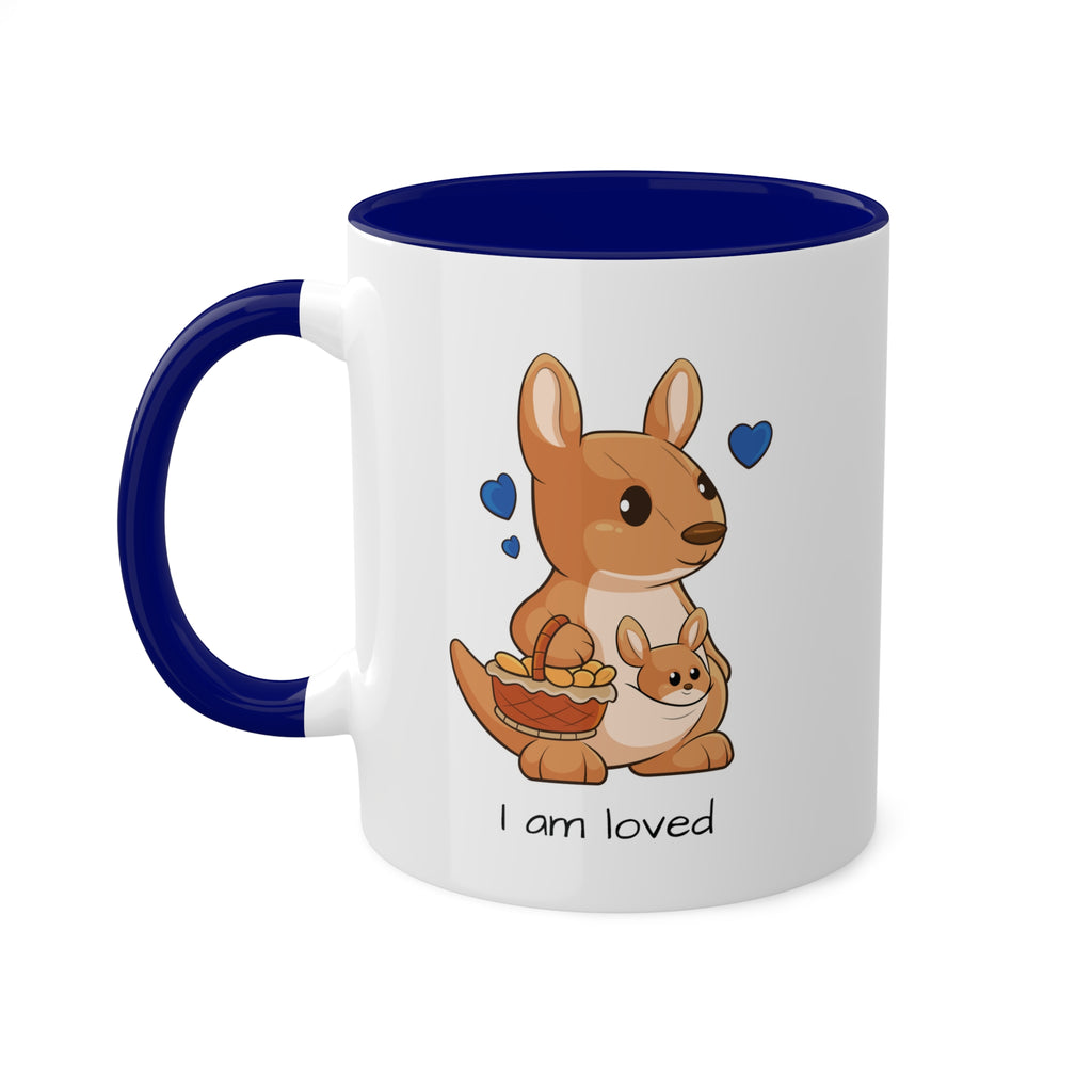 A white mug with a dark blue handle and interior and a picture of a kangaroo that says I am loved.