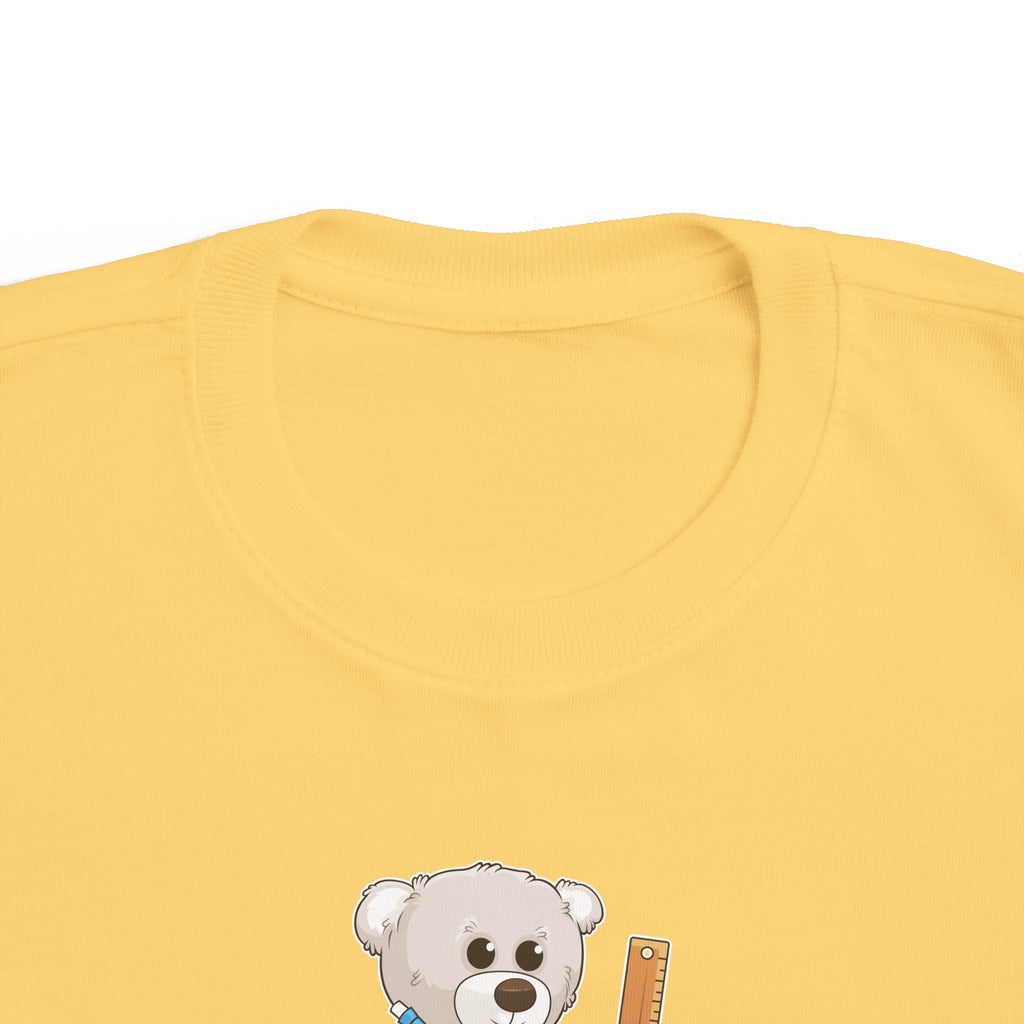 A close-up photo of the collar of a short-sleeve yellow shirt with a picture of a bear that says "Being beary perfect means trying my best".