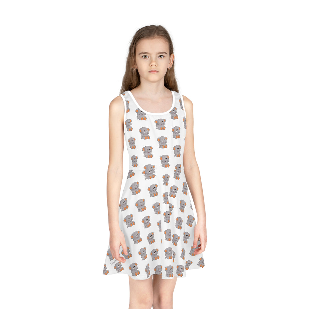 Front-view of a girl wearing a sleeveless white dress with a repeating pattern of an elephant.