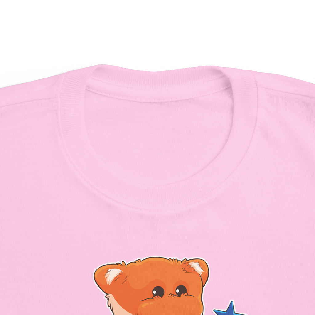 A close-up of the crew neckline of a short-sleeve light pink shirt with a picture of a fox that says I am a star.