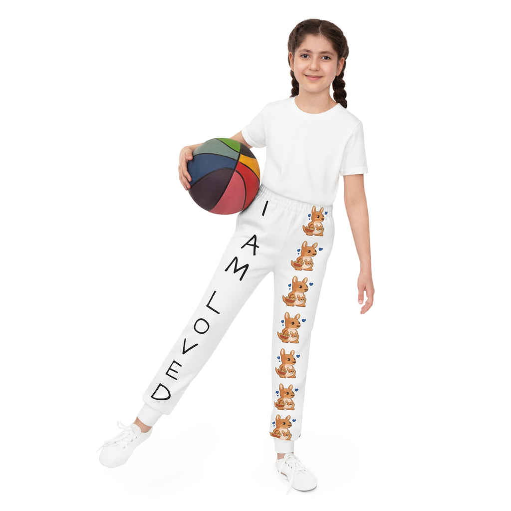 Front-view of a girl holding a basketball and wearing white sweatpants. The pants have a line of kangaroos down the front left leg and the phrase "I am loved" down the front right leg.