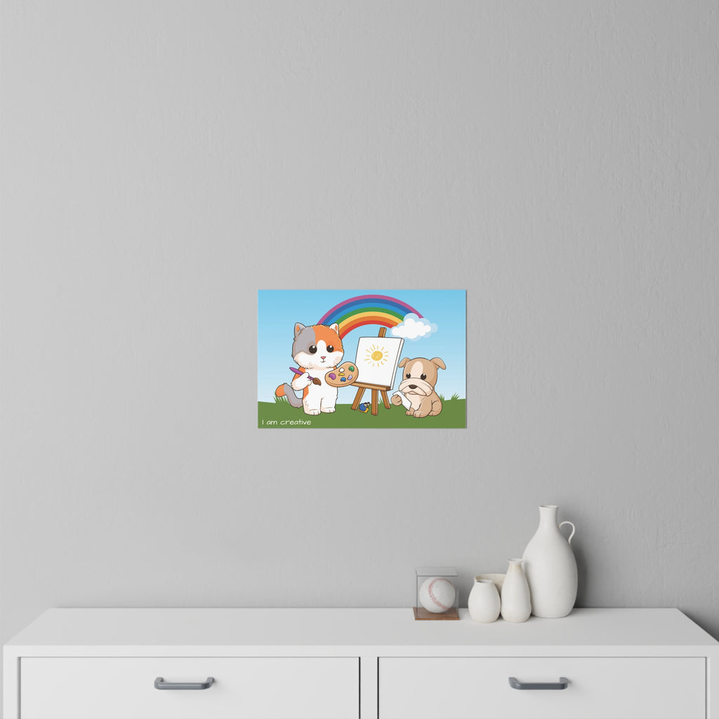 An 18 by 12 inch wall decal on a grey wall above a dresser. The wall decal has a scene of a cat painting on a canvas next to a dog, a rainbow in the background, and the phrase "I am creative" along the bottom.
