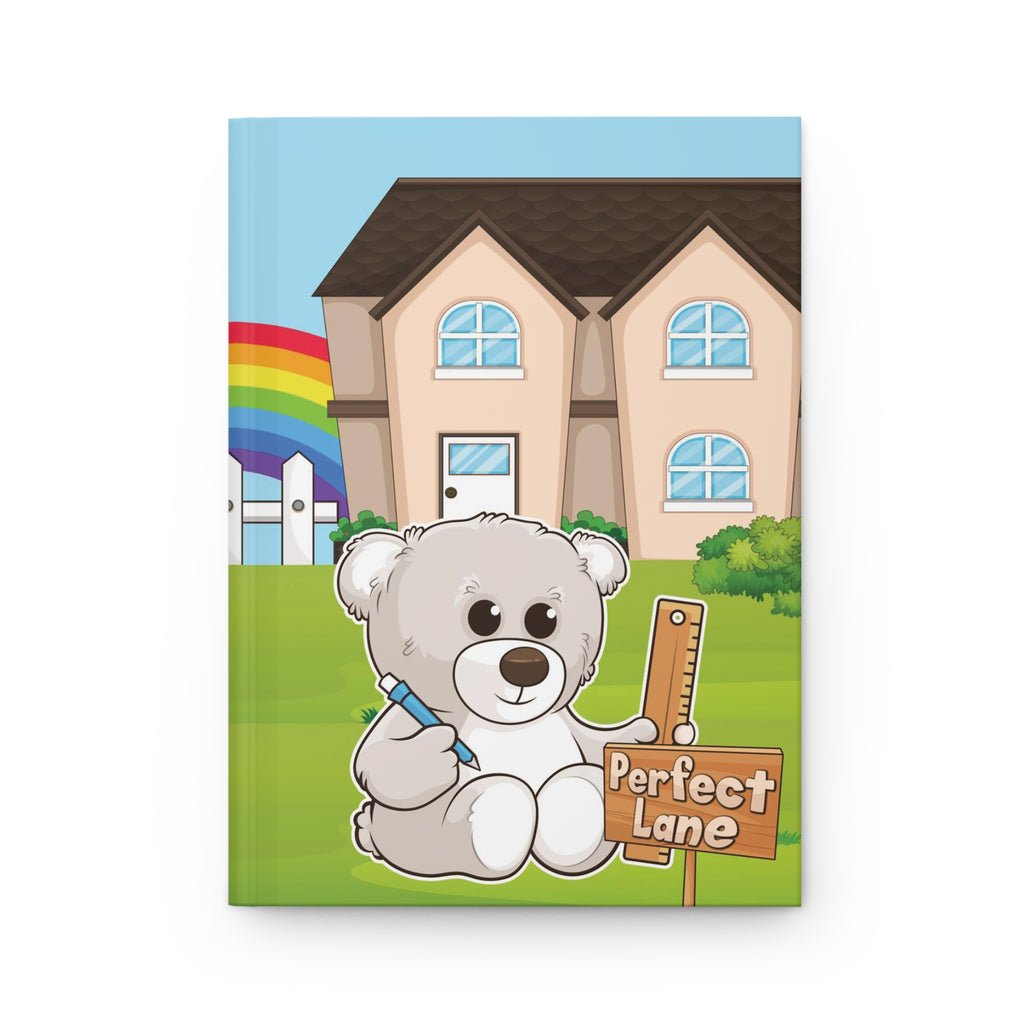 A hardcover journal laying flat. The journal cover is a scene of a bear in the yard of its house with a rainbow in the background.