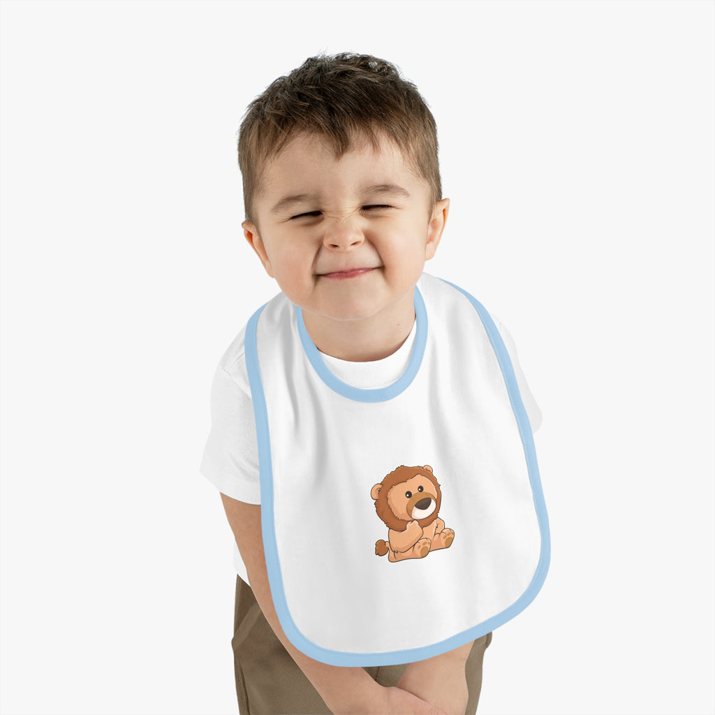 A little boy wearing a white baby bib with light blue trim and a small picture of a lion.