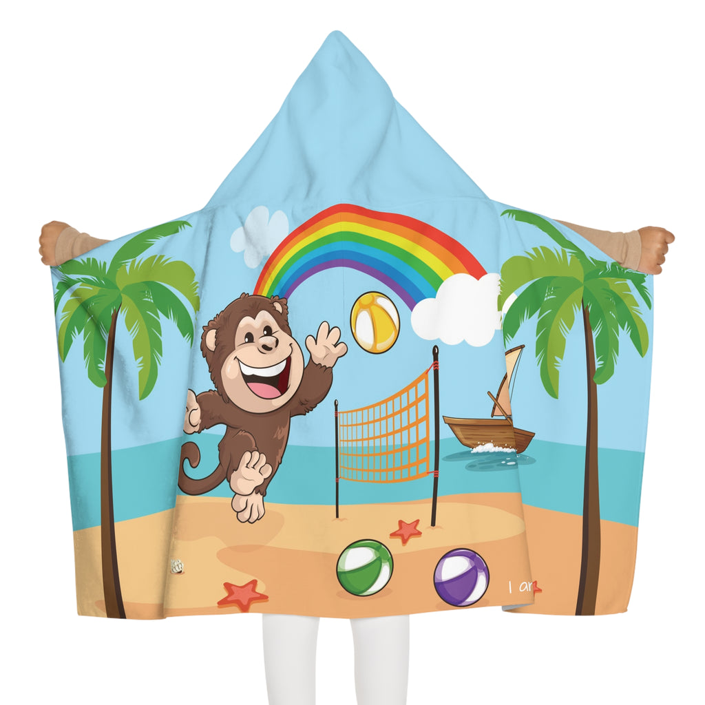 Back-view of a girl wearing a hooded towel and holding it open. The towel has a scene of a monkey playing volleyball on the beach, a rainbow in the background, and the phrase "I am fun" along the bottom.