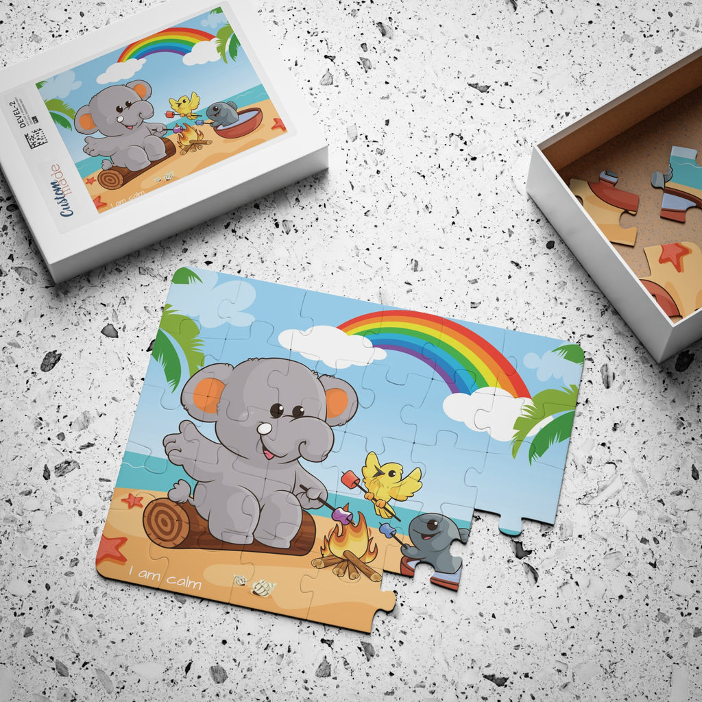 A 30 piece puzzle with a scene of an elephant having a bonfire with a bird and fish on the beach, a rainbow in the background, and the phrase "I am calm" along the bottom. The puzzle is mostly assembled next to its container box.