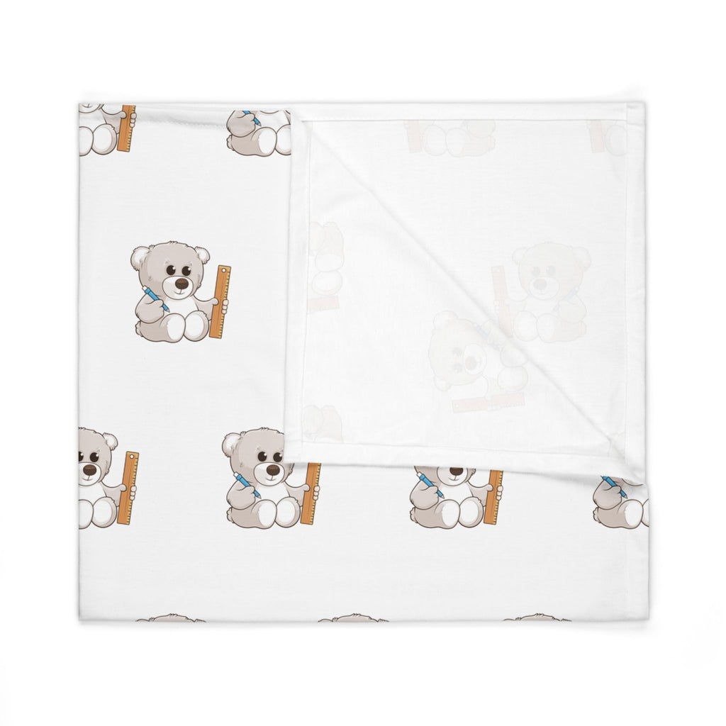A white swaddle blanket with a repeating pattern of a bear. The blanket is folded into a square.