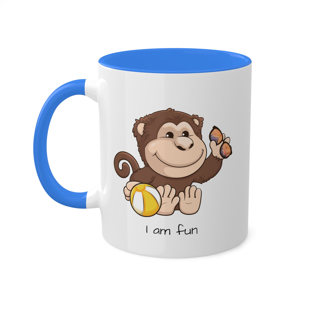 A white mug with a cambridge blue handle and interior and a picture of a monkey that says I am fun.