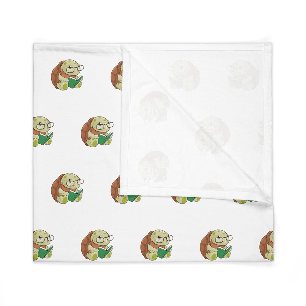 A white swaddle blanket with a repeating pattern of a turtle. The blanket is folded into a square.