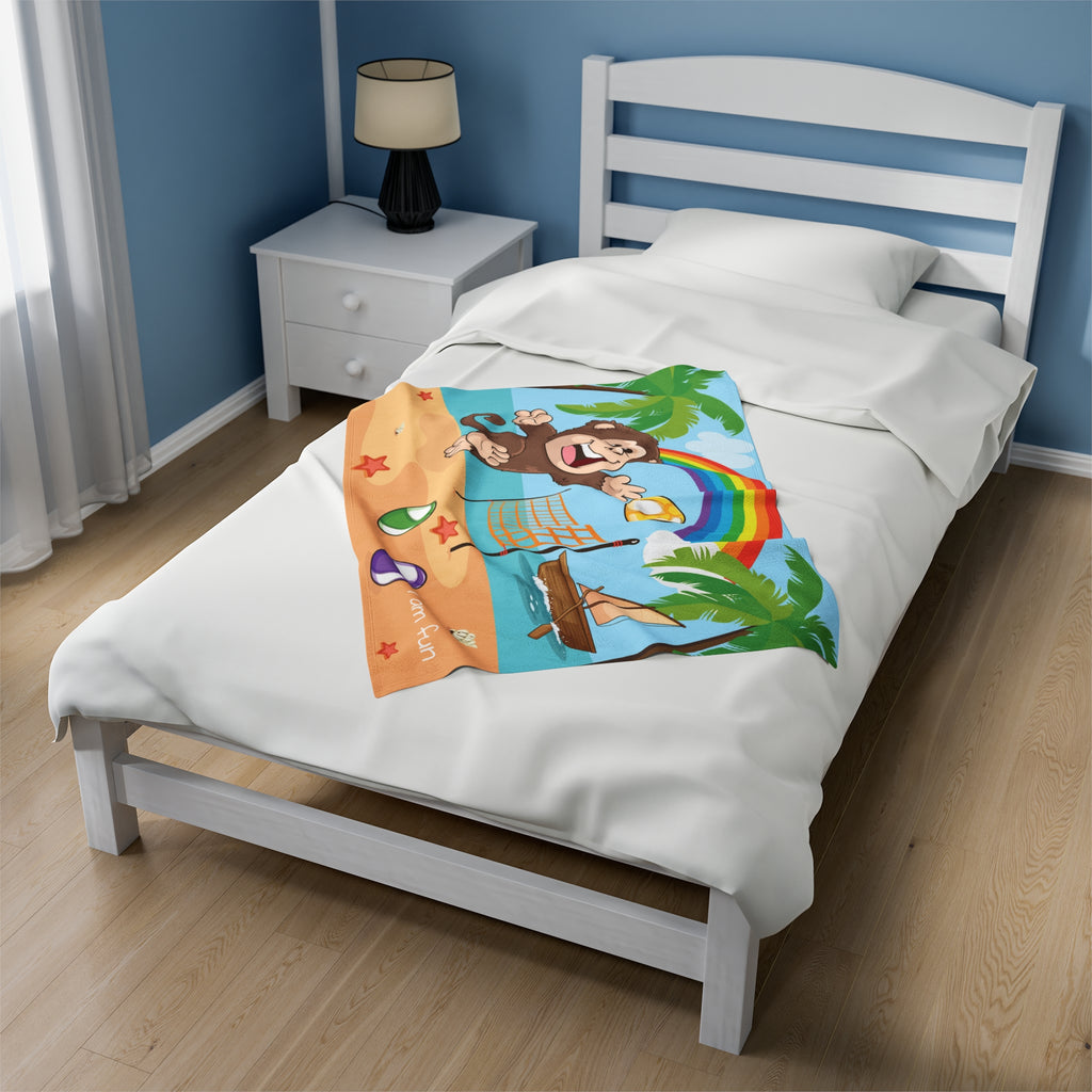 A 30 by 40 inch blanket on a twin-sized bed in a bedroom. The blanket has a scene of a monkey playing volleyball on the beach, a rainbow in the background, and the phrase "I am fun" along the bottom.