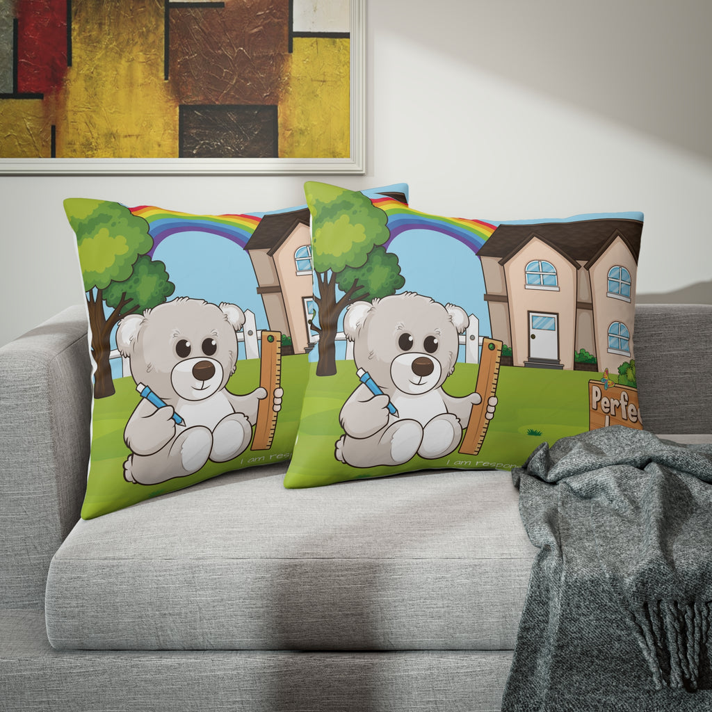 Two pillows sitting on a grey couch. The pillows have on pillowcases with a scene of a bear sitting in the yard of its house, a rainbow in the background, and the phrase "I am responsible" along the bottom.