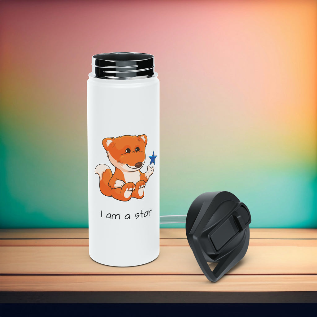 An 18 ounce white stainless steel water bottle sitting on a table with a black screw-on lid next to it. The bottle features a picture of a fox that says I am a star.