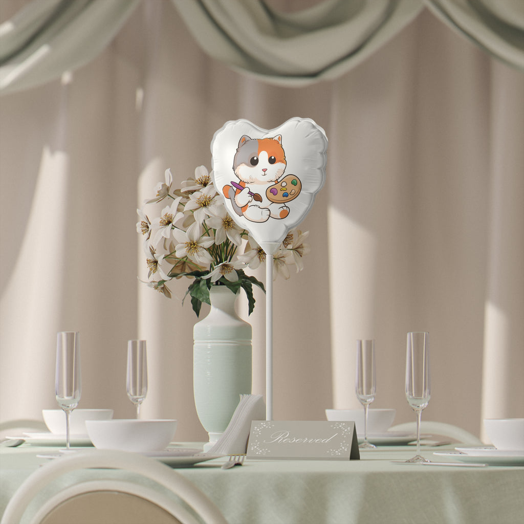 A heart-shaped white mylar balloon on a stick with a picture of a cat. The balloon sits on a table decorated for an event.