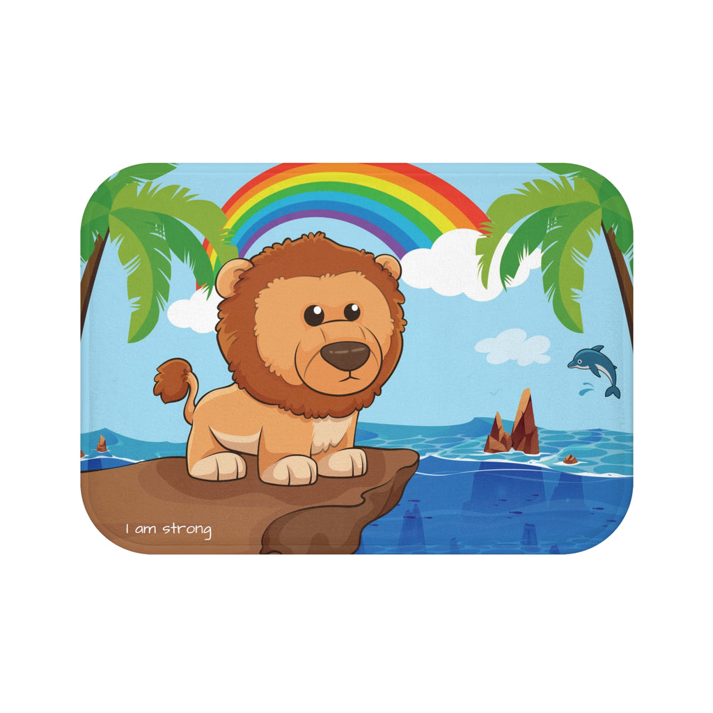 A 24 by 17 inch bath mat that has a scene of a lion standing on a cliff over the ocean with a rainbow in the background and the phrase "I am strong" along the bottom.