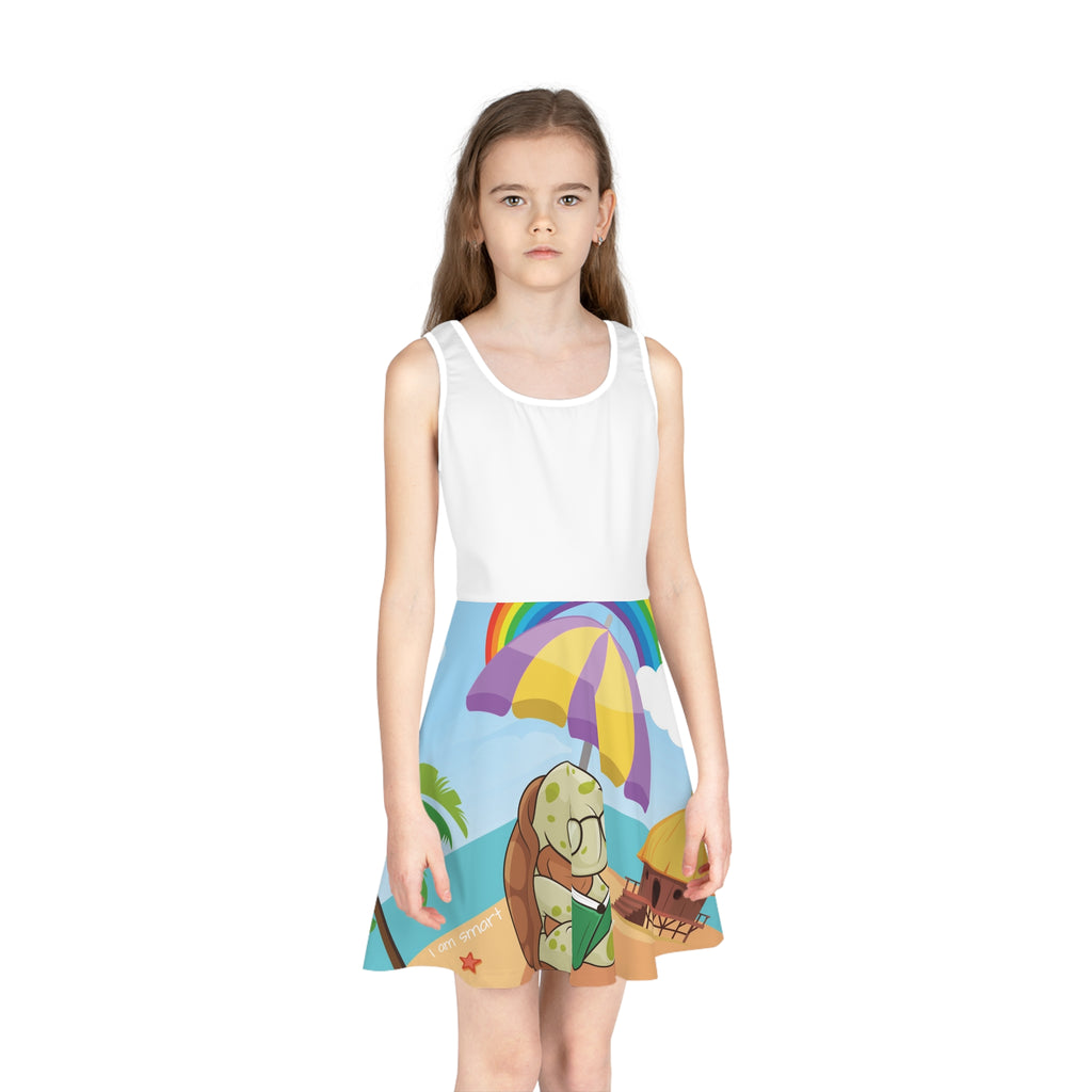 Front-view of a girl wearing a sleeveless dress. The dress has a white top and the skirt features a scene of a turtle reading a book under an umbrella on the beach and the phrase "I am smart".