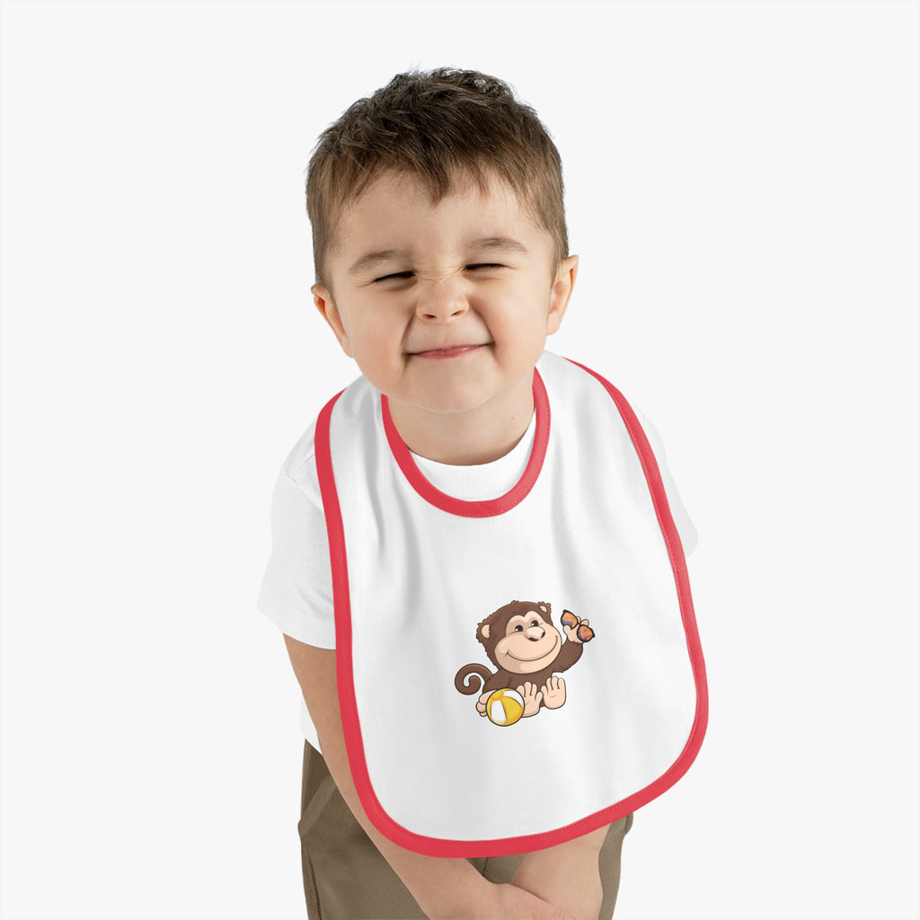A little boy wearing a white baby bib with red trim and a small picture of a monkey.