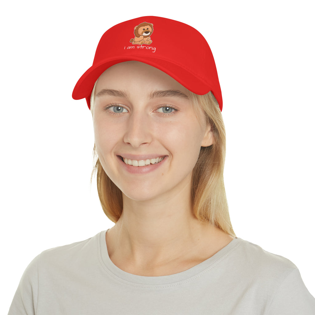 A female wearing a red baseball hat with a picture of a lion that says I am strong.