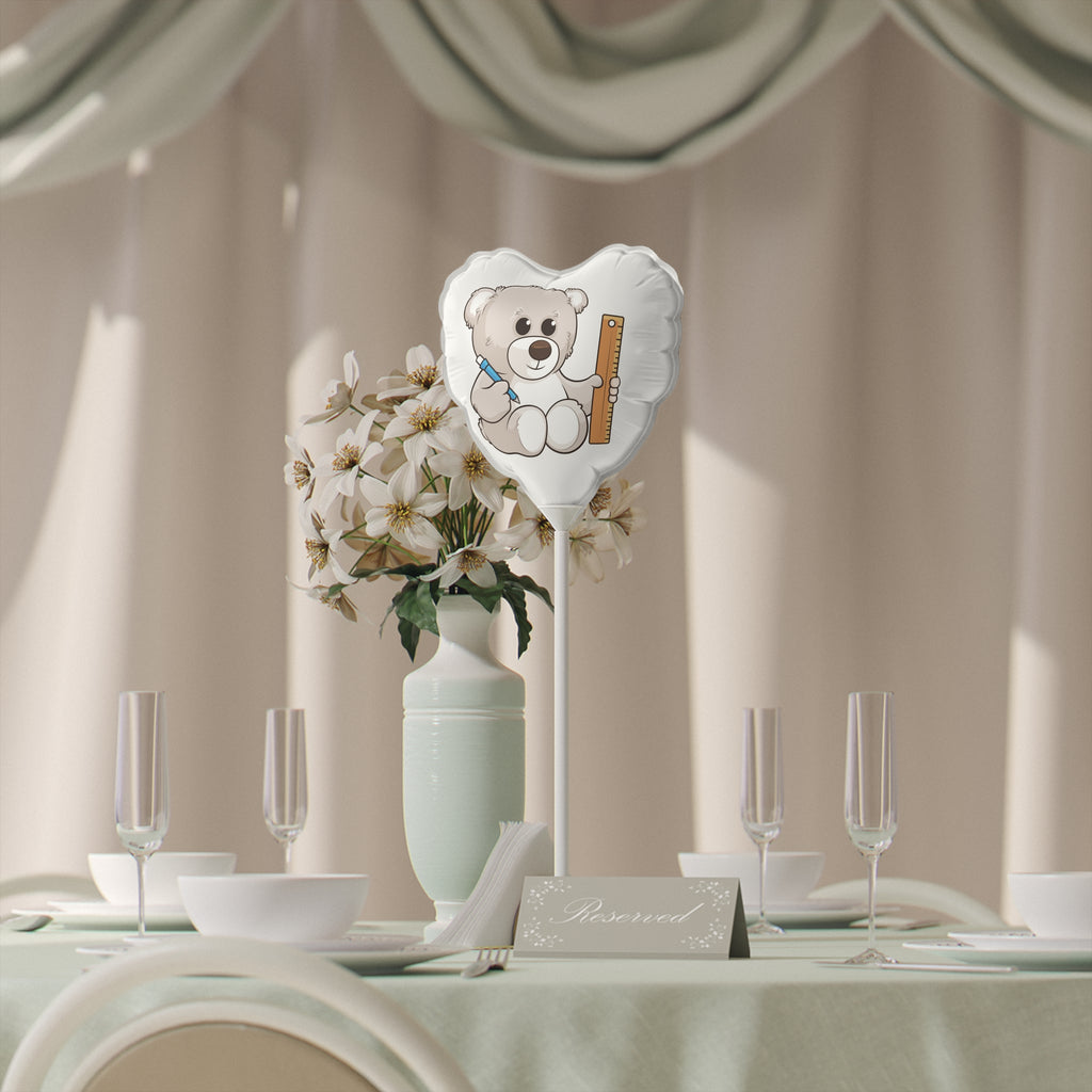 A heart-shaped white mylar balloon on a stick with a picture of a bear. The balloon sits on a table decorated for an event.