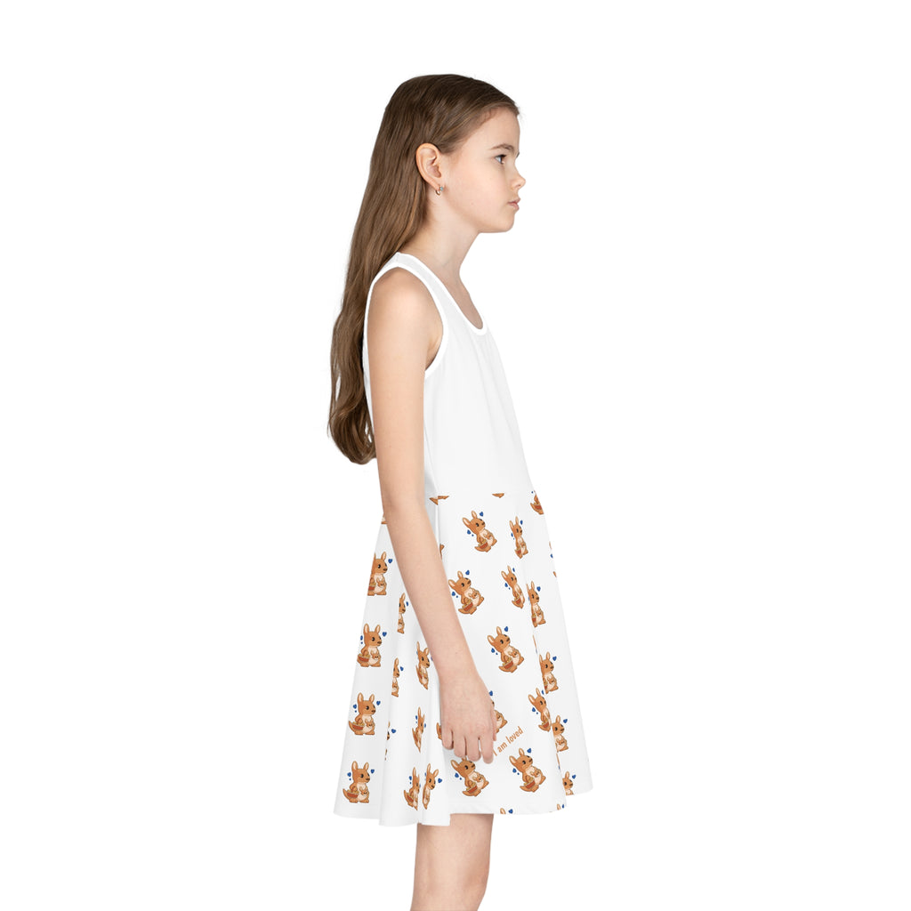 Right side-view of a girl wearing a sleeveless white dress with a white top and a repeating pattern of a kangaroo on the skirt.