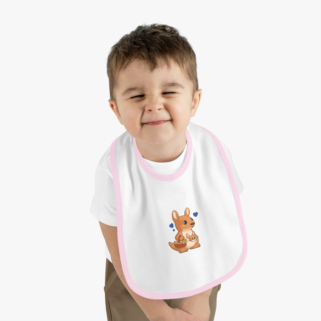 A little boy wearing a white baby bib with light pink trim and a small picture of a kangaroo.