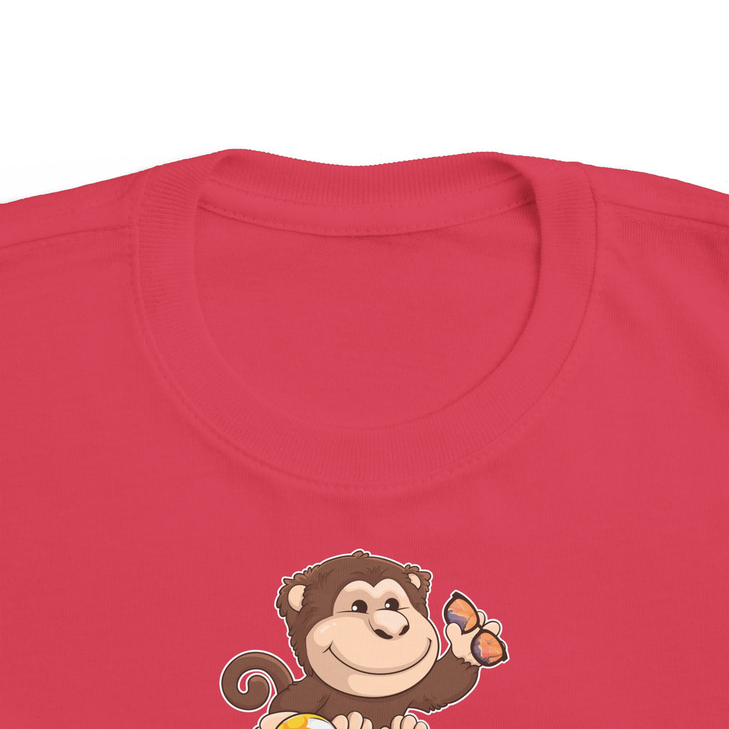 A close-up of the crew neckline of a short-sleeve red shirt with a picture of a monkey that says Ready to Play.